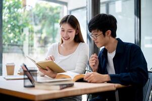 Two young Asian college students are studying and preparing for an exam together in a coffee shop. photo
