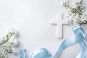 Composition with a Christian white wooden cross and flowers against muted white background photo