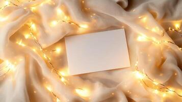 Blank card mockup lying on soft fabric, surrounded by warm fairy lights, highlighting festive atmosphere for personal messages or celebratory communication photo