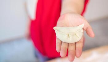 Young woman holding dumpling, showing her handmade art photo