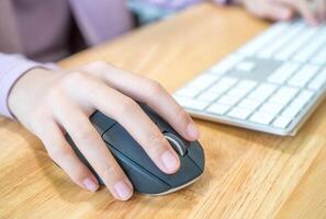 Girl's hand with computer mouse and keyboard photo