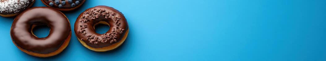 Variety of delicious donuts arranged on a bright blue background photo