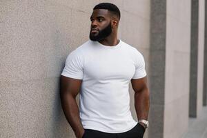 Man in a white shirt poses confidently against a gray wall in urban setting photo