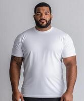 Strong man poses confidently in a plain white shirt against gray backdrop photo