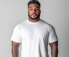 Strong man poses confidently in plain white shirt against light background photo