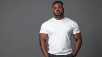 Strong man posing confidently in a simple white shirt against a gray backdrop photo