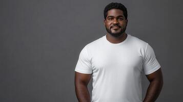 Confident man standing against a gray background in a plain white shirt photo