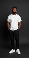 Man in casual outfit poses confidently against dark backdrop photo