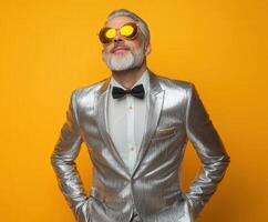 Elegant man in a shiny silver suit poses confidently against a yellow background photo