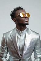 Man in stylish silver suit and sunglasses poses confidently in studio photo