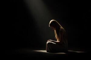 Woman in solitude illuminated by soft light in a dark space photo