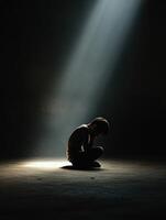 Boy in a dimly lit space reflecting in a beam of light photo