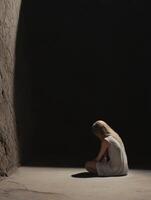 Lonely figure sitting in dark cavernous space with a somber atmosphere photo