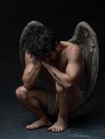 Man with angel wings expressing despair in a dark atmosphere photo