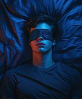 Young man resting with a sleep mask in a dimly lit room during nighttime photo