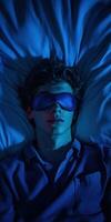 Young man sleeping peacefully in a dimly lit room with sleep mask photo