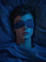 Sleeping boy wearing an eye mask in a darkened bedroom environment photo