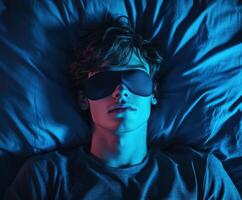 Young person resting on bed with sleep mask under blue light photo