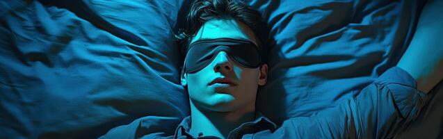 Young man resting peacefully wearing a sleep mask in a dimly lit room photo