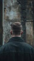 Portrait of a young man with stylish haircut against textured walls photo