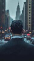 Man in a suit gazes at a bustling city street during twilight hours photo