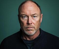 Intense portrait of a man with striking blue eyes against a dark background photo