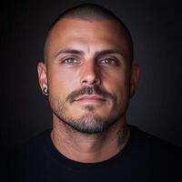 Man with short hair and strong features gazes confidently at the camera photo