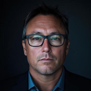 Professional portrait of an adult man with glasses in a dark setting photo