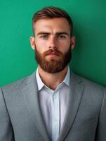 A young man stands tall with a well-groomed beard and a stylish suit photo
