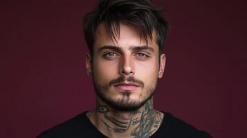 Young man with tattoos poses against a dark purple background photo