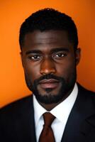 A well-dressed man stands confidently against a vibrant orange backdrop photo
