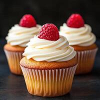 Cupcakes with creamy frosting and fresh raspberries on top photo