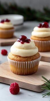 Delicious cupcakes topped with cream frosting and raspberry jam on wooden boards photo