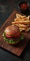 Juicy burger with lettuce, tomato, and crispy fries on a wooden board photo