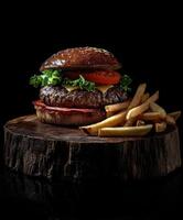 Juicy gourmet burger with crispy fries served on rustic wooden board photo
