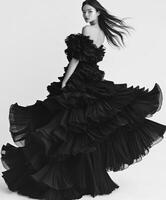 Woman in a black ruffled dress spins on a minimalist background photo