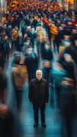 Senior man stands still amid a blurred crowd in a bustling urban environment photo