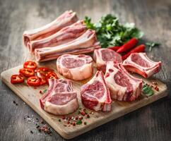 Freshly cut lamb chops and bones arranged on a wooden cutting board photo