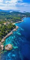 Ocean view with rocky shore and lush greenery near a coastal village photo