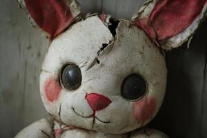 Vintage worn-out stuffed bunny with cracked face and faded colors photo