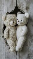 Two teddy bears cuddling through a torn wall in a cozy setting photo