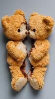 Two torn teddy bears facing each other on a gray surface photo