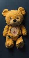 Worn teddy bear resting on a dark background showing signs of love and wear photo