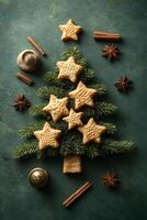 Christmas tree made of fir branches and star shaped cookies decorated with cinnamon sticks and anise stars on green background photo