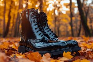 Shiny black boots resting on vibrant autumn leaves in a forest photo