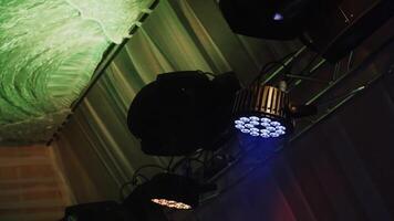 Stage lighting equipment. Spotlights turning and sparkling. Automated luminaire hang under hall ceiling and rotate in dark interior. video