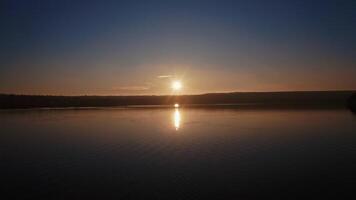 River at sunset. Setting sun reflects on the water surface in the evening. Beautiful view of the lake with setting sun on the evening sky. video