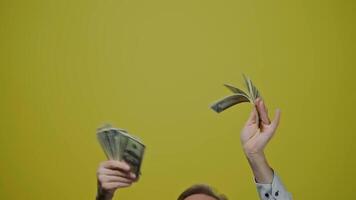 Good-looking joyful man with money on yellow background. Satisfied modern gray-bearded grandfather posing on camera with many dollar bills. Slow motion. video