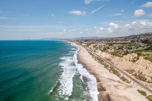 Expansive aerial view of San Clemente coastline with waves crashing on sandy beach under a clear sky photo