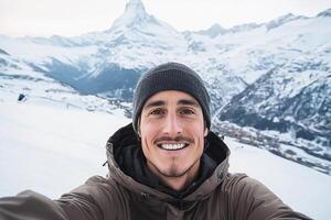 A man taking a selfie in front of a snowy mountain photo
